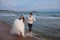 Happy bride and groom run along ocean shore. Newlyweds having fun at wedding day on tropical beach