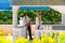 Happy bride and groom standing next to the stone gazebo amid beautiful tropical landscape. Sea, sky, flowering plants and palm tr