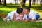 Happy bride and groom on their wedding lies on the grass in park and kiss