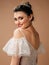 Happy bride in a white wedding dress posing in studio on brown background. Marriage concept. Posh wedding dress with lace ruffled