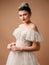 Happy bride in a white wedding dress posing in studio on brown background. Marriage concept. Posh wedding gown with lace ruffled s