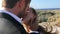 A happy bridegroom kisses the bride on the beach in a sunny windy day. close-up