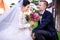 Happy bridegroom looking at beautiful bride holding bouquet outdoors