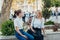 Happy bright positive moments of two stylish girls hugging and looking at the phone, discussing something on the street in the