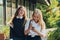 Happy bright positive moments of two stylish girls hugging and looking at the phone, discussing something on the street in the