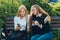 Happy bright positive moments of two stylish girls hugging and looking at the phone, discussing something on the street in the