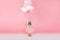 Happy brightful image of excited joyful little girl in tulle skirt holding ribbon with flying balloons  on pink