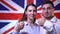 Happy british family handsome man and woman on british flag background, smiling and looking at the camera. British