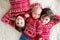 Happy brothers, baby and preschool children, hugging at home on white blanket, smiling