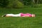 Happy brown haired girl relaxing on ground lying on stomach on mat.