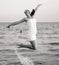 Happy brunette girl jumping over the sea. Stylized as retro photo