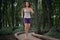 Happy brunette girl in shorts and a tank top runs in a summer park.