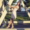 Happy brunette woman in a dress relaxing fun in the park leaning on wooden piles in the enjoy your vacation, fashion