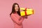 Happy brunette woman in pink sweater holding in hands unboxed present and looking at camera with toothy smile, satisfied with gift