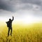 Happy business man jumping in yellow rice field and rainclouds