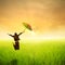 Happy business umbrella woman jumping in green rice field and sunset
