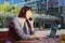 Happy business woman talking on mobile phone while working on laptop