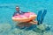 Happy businessman in flippers on an inflatable donut in the sea. Summer vacation concept