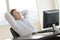 Happy Businessman With Hands Behind Head Sitting At Desk