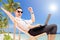 Happy businessman with a laptop on a beach