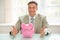 Happy businessman with piggybank on desk