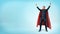 A happy businessman in a superhero red cape standing in victory pose on blue background.