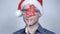 Happy businessman wearing santa hat smiling over grey background.