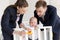 happy businesspeople playing with little son in baby crib