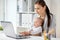 Happy businesswoman with baby and laptop at office