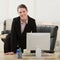 Happy businesswoman leaning on desk