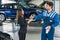 Happy Businesswoman Receiving Car Key From Mechanic At Garage