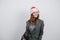 Happy businesswoman in Santa hat smiling on grey background. Attractive girl dreamily looking aside. Christmas concept.