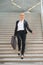 Happy businesswoman walking downstairs with briefcase