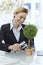 Happy businesswoman watering potted plant