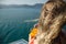 Happy busty woman on yacht. Lady in girl in coral bikini holding orange fresh drink. Cool drink and fresh aquamarine sea