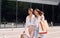 Happy buyers. Two female friends have a shopping day. Walking outdoors with bags