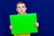 Happy calm caucasian child boy holding a poster for your information on the blue background