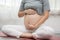 Happy Calm Pregnant Woman sit on yoga mat and stroking her big belly with love at cozy home,Pregnancy of young woman enjoy with