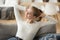 Happy calm woman relaxing, stretching on comfortable sofa at home