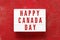 HAPPY CANADA DAY written in lightbox on red background. Independence day date. Top view