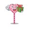 Happy candy heart lollipop character having a gift box