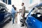 Happy Car Buyers Handshaking With Seller Standing In Dealership Showroom