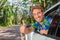 Happy car driver man driving safe on road trip travel doing thumbs up in satisfaction of cars rental. Smiling young male