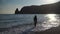 happy carefree sensual woman with long hair in black swimwear posing at sunset beach. silhouette of young beautiful