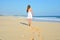 Happy carefree woman walking on beach celebrating her freedom. Summer woman background of the ocean and sand. Back view of girl.