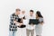 Happy Casual Group Of Four Multiethnic People Standing Over White Background, using laptop and tablets while working