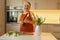 Happy Caucasian 30s woman taking care of cut fresh bouquet of tulips in kitchen. Housewife hands of woman cutting flower