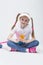 Happy Caucasian Blond Girl wearing Visor Sitting on Floor with Cup of Juice