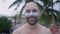 Happy caucasian bold bearded man with blue paint of face showing toothy smile during a tropical island vacation - face