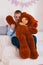 happy caucasian boy hugs big brown stuffed bear